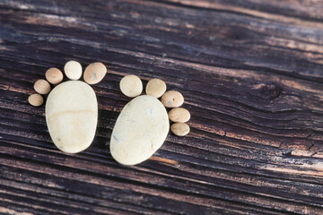 Funny human footprints from stones on a wooden background.
