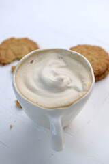 Latte or Cappuccino with frothy foam, coffee cup over rustic background