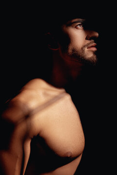 Handsome young guy. He has a model appearance. His torso is bare. The man looks away