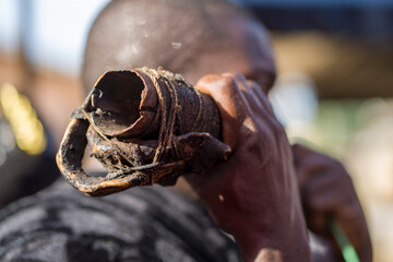 selective focus of african man holding an object in front of his face- close up image of horn- traditional music concept