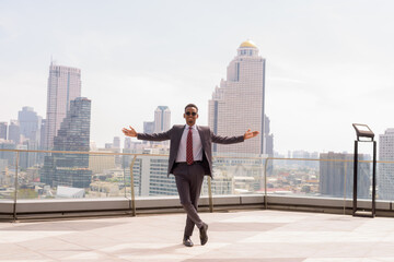Full length portrait of African businessman wearing suit and tie outdoors in city while standing
