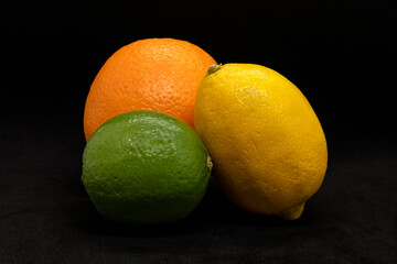 An orange a lime and a lemon on black bacground with shallow depth of field