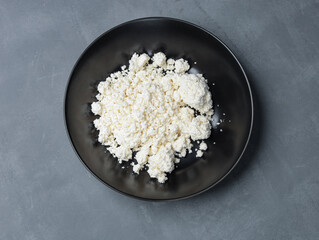 natural cottage cheese in a black plate on a gray table - 478158733