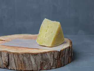 cheese on a wooden stand with paper on a gray background - 478158942