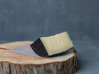 cheese on a wooden stand with paper on a gray background - 478158995