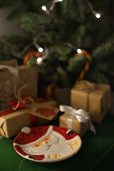 Empty plate near christmas tree and gifts, with lights bokeh at home