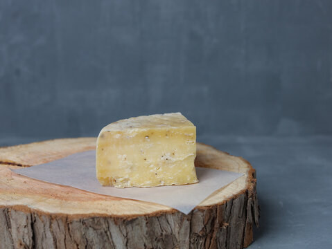 cheese on a wooden stand with paper on a gray background