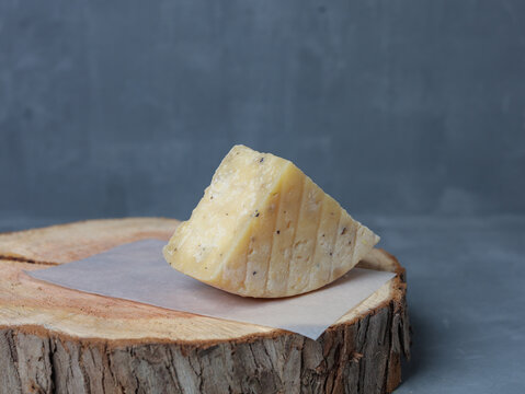 cheese on a wooden stand with paper on a gray background