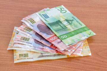 Norwegian krone (NOK) banknotes on wooden table.