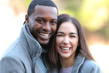 Happy interracial couple laughing at camera in winter
