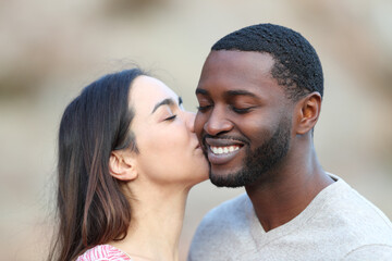 Obraz premium Caucasian woman kissing on cheek a man with black skin