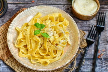 Italian food . Fresh home made  tagliatelle vegetarian  egg pasta  with ,parmesan cheese ,fresh parsley  and black pepper.Pasta cacio e pepe