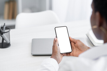 Application ad. Mobile advertisement. Phone gadget. Internet shopping. Unrecognizable woman browsing on smartphone blank white copy space mockup screen at desk.