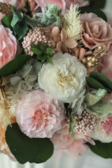 Beautiful preserved flower bouquet in ceramic white vase on white table. Stylish bouquet in peach tones closeup.
