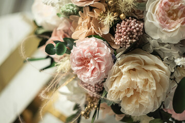 Beautiful preserved flower bouquet in ceramic vase on white table. Stylish bouquet in peach tones closeup.