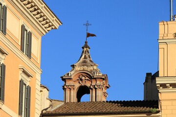 Fototapeta na wymiar Church Spire with Sculpted Angel Head Against a Bright Blue Sky in Rome, Italy