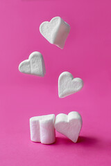 Fototapeta premium Minimalist Valentine's day. White marshmallow hearts on pink pastel background. Composition for Valentins Day, Mother's Day, March 8 or Women's Day.
