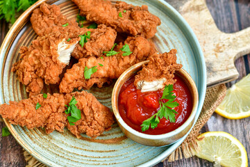 Crispy  deep fried   chicken strips and wedges potato. Breaded  with cornflakes chicken  breast fillets  with chilly peppers and fresh   basil on wooden rustic background