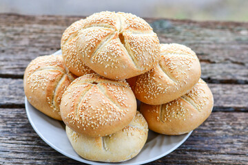 Tasty fresh  crisp  bakery product.   Baked bund bread with sesame seeds on wooden rustic background. Outdoor in a village