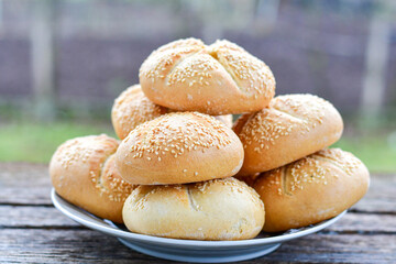 Tasty fresh  crisp  bakery product.   Baked bund bread with sesame seeds on wooden rustic background. Outdoor in a village