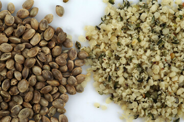 Two heaps of raw hemp seeds, whole and shelled, .on a white background. Selective focus..