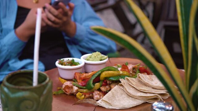 Mexican food on table close-up. Traditional tex mex cuisine. Putting cooked burrito, tacos served with meat and vegetables, tomato soup with cilantro, guacamole. American dishes top view. 4k