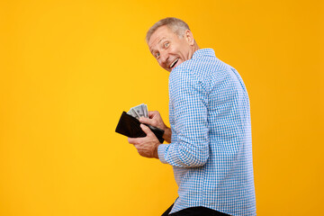 Excited mature man holding taking money from wallet