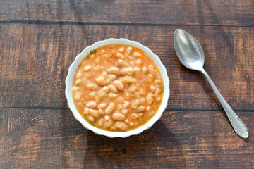   Homemade bean soup .Steamed white beans in tomato sauce  on a wooden background  