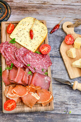 Italian  dried thinly sliced   artisan  pork Salami Milano ,  mediterranean Parmesan cheese, tomatoes   and fresh basil on wooden background .Rustic  home made Italian snack.