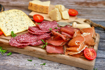 Italian  dried thinly sliced   artisan  pork Salami Milano ,  mediterranean Parmesan cheese, tomatoes   and fresh basil on wooden background .Rustic  home made Italian snack.