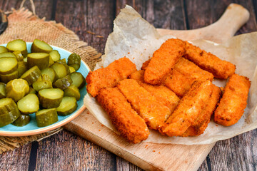 Close up of   Crispy breaded  deep fried fish fingers with breadcrumbs served  with remoulade sauce and  lemon Cod Fish Nuggets on rustic wood table background