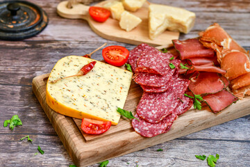 Italian  dried thinly sliced   artisan  pork Salami Milano ,  mediterranean Parmesan cheese, tomatoes   and fresh basil on wooden background .Rustic  home made Italian snack.