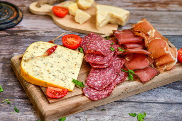 Italian  dried thinly sliced   artisan  pork Salami Milano ,  mediterranean Parmesan cheese, tomatoes   and fresh basil on wooden background .Rustic  home made Italian snack.