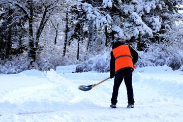 Naklejka premium A worker in a yellow vest cleans the city street, park from fresh snow in winter. Dnipro, Dnipropetrovsk, Ukraine