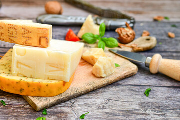  Set of different kinds ot delicious   Italian hard  cheeses,  cheese knives  and walnuts on wooden cheese board.Parmesan. Top view.