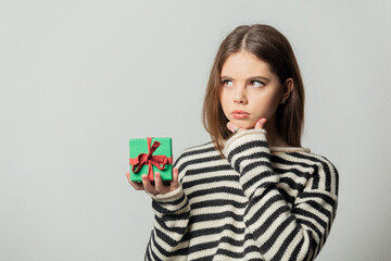 Beautiful girl in striped sweater with gift box on white background