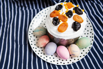 Easter eggs and Easter cake lie on a plate lying on a striped blue apron. Easter religious holiday concept.