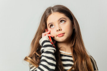Beautiful girl in striped sweater talking by mobile phone on white background