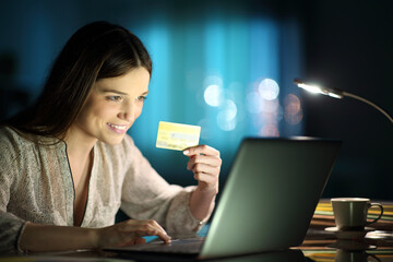 Happy woman holding credit card buying on line at home