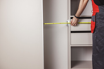 Master takes measurements during the installation of the wardrobe and assembling furniture