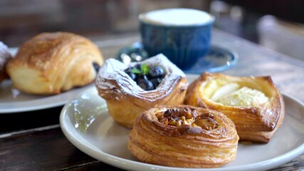 Sweet pastries in cafe. Puff pastry, fresh buns with powdered sugar, berries, caramel nuts and baked apples. Tasty bakery on plates and cup of coffee. Breakfast in rustic cafe with freshly baked bun