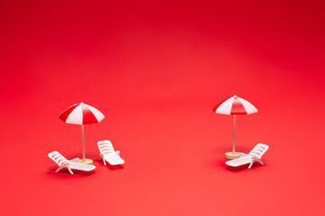 Two sun loungers and red umbrellas on a red background.
