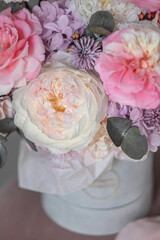 A luxurious bouquet of flowers in a hat box. Composition with pink and white flowers and eucalyptus in a box. Modern Floristry.