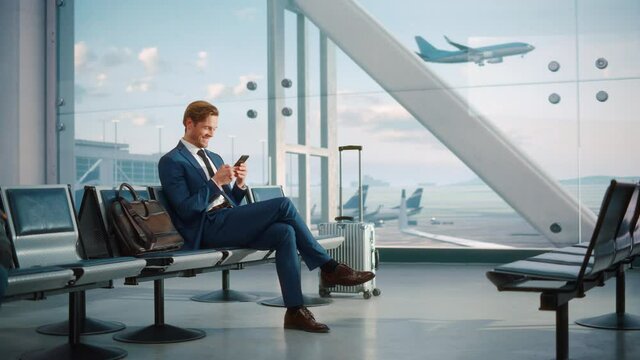 Airport Termina Flight Wait: Successful Businessman Uses Smartphone, Closes e-Business Deal and Celebrates Victory. Traveling Entrepreneur Remote Work Online in Boarding Lounge of Airline Hub