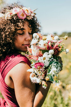 Black woman holds bouquet of pink flowers up to face