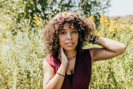 Woman looks into camera while sitting in field of wild flowers