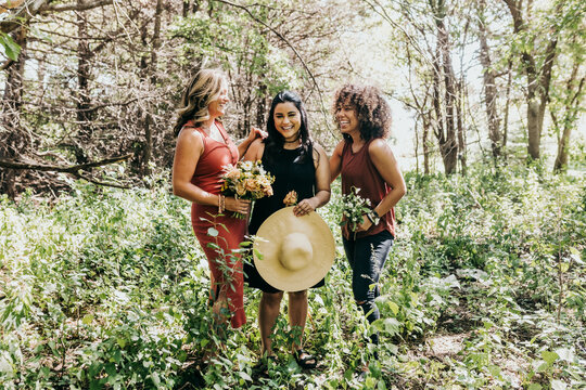 Group of women laughing in a forest surrounded by plants