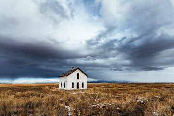 storm clouds loom over white abandoned house in desert, Colorado