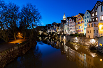 Fototapeta na wymiar “Neckarfront“ illuminated historic facades of old town of Tuebingen on Neckar River in southern Germany an a winter evening with colorful reflections, Hölderlin Tower and Church