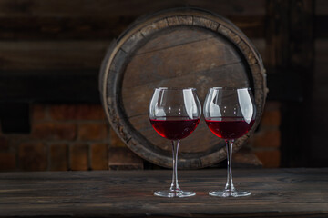 Wine glasses with tall stem. Old oak barrel in a dark wine cellar at the winery. Aging cellaring wine tasting